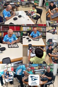 A imagem é uma montagem vertical com várias fotos tiradas dentro de uma biblioteca, com prateleiras cheias de livros coloridos ao fundo.
Na parte de cima, há dois homens adultos de camisa azul clara com estampa esportiva jogando em tabuleiros com peças táteis, junto com um menino de camiseta verde-clara, sentado à mesa com um tabuleiro próprio e um copo vermelho.
No meio da montagem, aparecem dois closes de um dos homens de camisa azul concentrado nas peças, com o tabuleiro tátil sobre a mesa e um relógio digital de xadrez ao lado.
Mais à direita, há fotos de um homem de camiseta preta usando notebook sobre a mesa, com um tabuleiro de peças táteis à frente dele.
Mais abaixo, há uma imagem do menino de camiseta verde-clara mexendo nas peças de um tabuleiro, visto por trás.
Na parte inferior, há uma foto de um homem de camisa azul auxiliando uma mulher sentada ao tabuleiro, e ao lado direito outro homem, de camiseta preta e calça com listras brancas, sorrindo sentado à mesa com um tabuleiro à frente.
No centro inferior da montagem há um selo com logotipo azul escrito:
“CBCP
CLUBE APOIADO”.